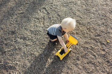 Hoher Blickwinkel eines Jungen, der mit einem Spielzeug-Erdbewegungsfahrzeug auf dem Boden spielt - CAVF59898