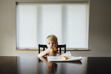 Porträt eines Jungen ohne Hemd, der zu Hause am Tisch sitzt und Brot isst - CAVF59919