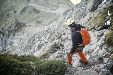 High angle view of hiker with backpack standing on rocks during mountain climbing - CAVF60000