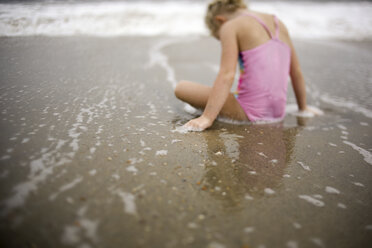 Rückansicht eines am Strand sitzenden Mädchens - CAVF60008