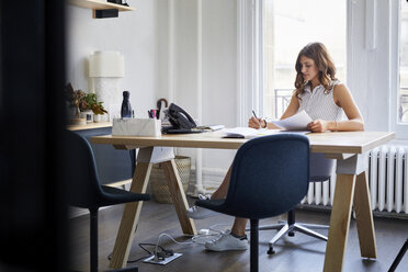 Geschäftsfrau bei der Arbeit mit Dokumenten am Schreibtisch im Büro - CAVF60078