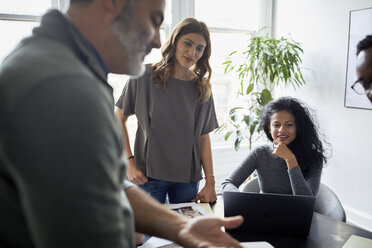 Businessman explaining to female colleagues in creative office - CAVF60109