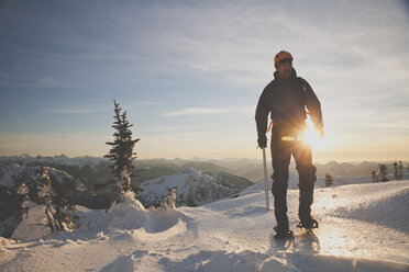 Wanderer in voller Länge mit Eispickel beim Bergsteigen auf schneebedeckten Bergen gegen den Himmel bei Sonnenuntergang - CAVF60120