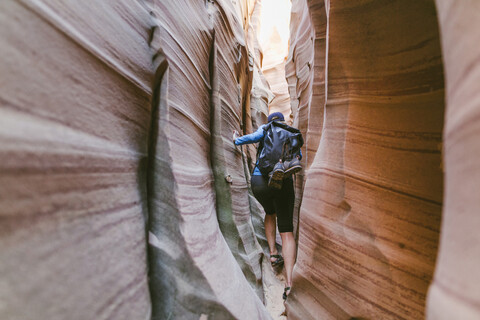 Wanderer in voller Länge mit Rucksack beim Canyoning inmitten enger Schluchten, lizenzfreies Stockfoto