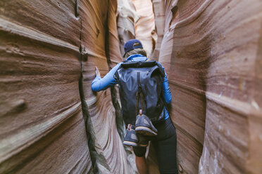 Rear view of hiker with backpack canyoneering amidst narrow canyons - CAVF60147