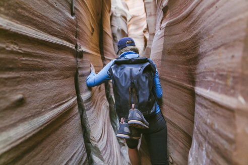 Rückansicht eines Wanderers mit Rucksack beim Canyoning inmitten enger Schluchten - CAVF60147