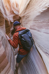 Rear view of hiker with backpack canyoneering amidst canyons - CAVF60150