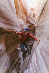 Full length portrait of hiker canyoneering amidst narrow canyons - CAVF60152
