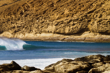 Mid distance view of person surfboarding in sea against mountain - CAVF60184