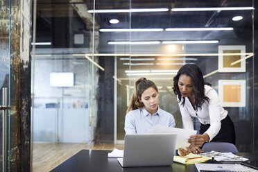 Businesswomen discussing over paperwork at conference table in board room - CAVF60266