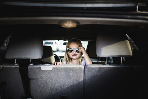 Porträt eines Mädchens mit Sonnenbrille, das im Auto sitzt, lizenzfreies Stockfoto