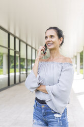 Porträt einer lächelnden reifen Frau am Telefon im Freien - JUNF01595