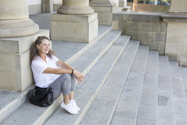 Content mature woman sitting on stairs having a rest - JUNF01601