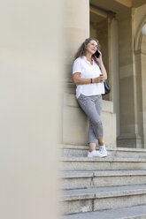 Reife Frau mit Kaffee zum Telefonieren im Freien - JUNF01607