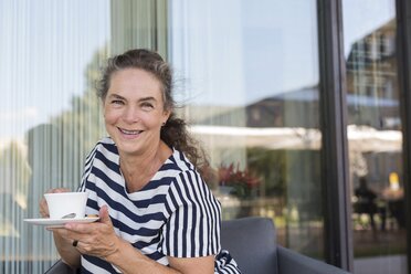 Porträt einer lächelnden reifen Frau mit einer Tasse Kaffee im Freien - JUNF01621