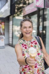 Porträt einer lächelnden reifen Frau mit Eiswaffel in der Stadt - JUNF01633