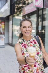 Portrait of smiling mature woman with ice cream cone in the city - JUNF01633