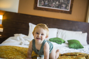 Baby girl on bed in hotel room - RUNF00403