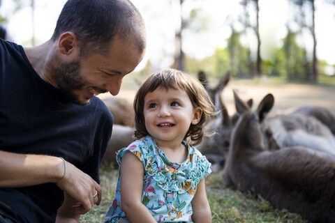 Australien, Brisbane, lachender Vater mit seiner kleinen Tochter vor einer Gruppe von Kängurus, lizenzfreies Stockfoto