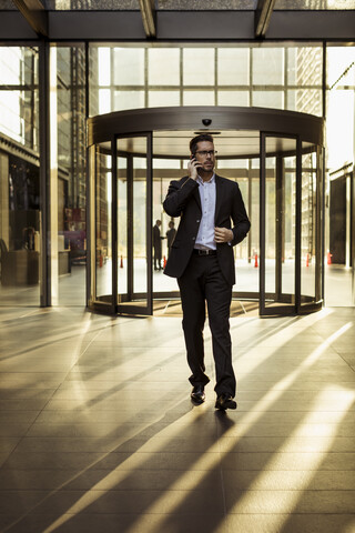 Geschäftsmann am Mobiltelefon im Foyer eines Bürogebäudes, lizenzfreies Stockfoto