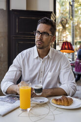 Businessman having breakfast in a cafe - MAUF01954