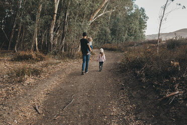 Full length of siblings walking in forest - CAVF60341