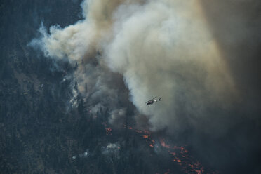 Wasserflugzeug beim Flug über die Berge während eines Waldbrandes im Grand Teton National Park - CAVF60354