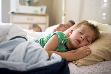 Father and sons sleeping on bed at home - CAVF60397