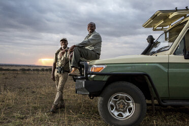 Porträt von männlichen Freunden im Geländewagen im Serengeti-Nationalpark bei Sonnenuntergang - CAVF60409