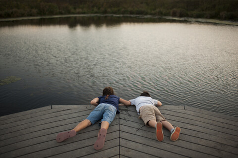 Hohe Winkel Ansicht der sorglosen Geschwister liegen auf Pier über See im Park, lizenzfreies Stockfoto