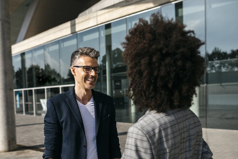 Two colleagues talking outside office building - JRFF02187