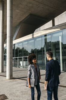 Two colleagues talking outside office building - JRFF02188