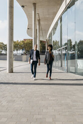 Zwei Kollegen gehen vor einem Bürogebäude spazieren - JRFF02189