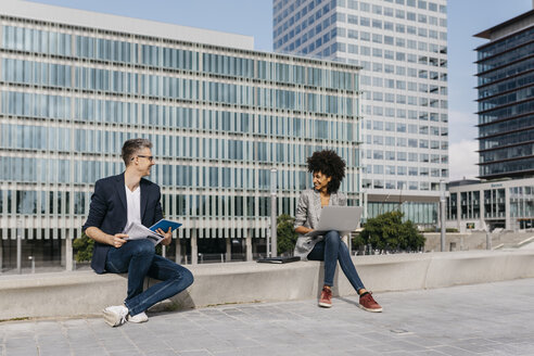 Two confident colleagues working together outside office building - JRFF02195