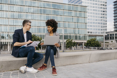 Two confident colleagues working together outside office building - JRFF02197