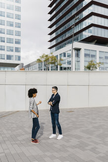 Two colleagues talking outside office building - JRFF02212