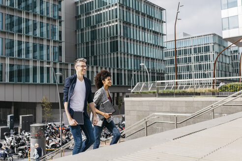 Two colleagues walking outside office building in the city - JRFF02217