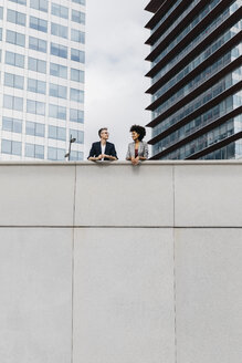 Two colleagues talking outside office building - JRFF02218