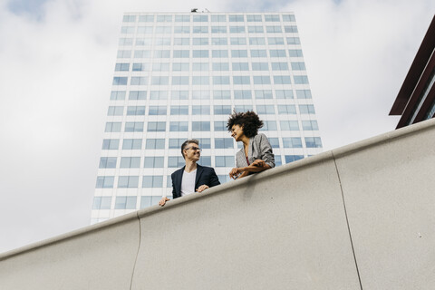 Zwei Kollegen unterhalten sich vor einem Bürogebäude, lizenzfreies Stockfoto