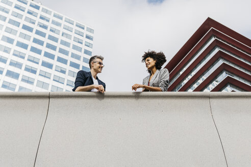 Two colleagues talking outside office building - JRFF02220