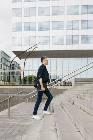 Businessman walking on stairs outside office building in the city stock photo