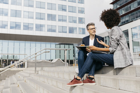 Two colleagues working together outside office building - JRFF02227