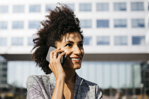 Portrait of smiling businesswoman on cell phone outside office building stock photo