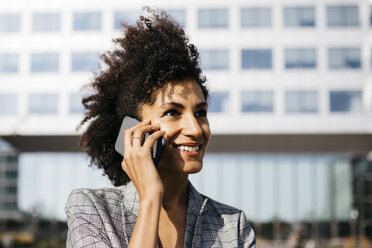 Porträt einer lächelnden Geschäftsfrau am Mobiltelefon vor einem Bürogebäude - JRFF02229