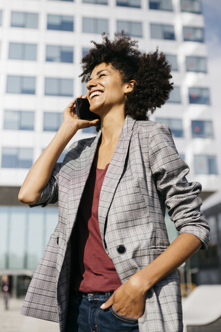 Laughing businesswoman on cell phone outside office building stock photo