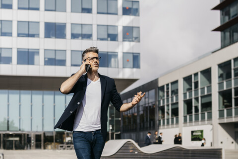 Verärgerter Geschäftsmann mit Mobiltelefon vor einem Bürogebäude, lizenzfreies Stockfoto