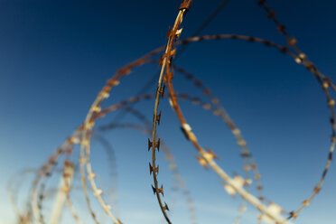 Part of barbed wire fence against blue sky - DASF00080