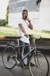 Young man with bicycle and cell phone on the go - ERRF00394