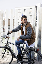 Junger Mann mit Fahrrad in der Stadt - ERRF00407