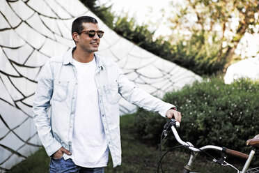 Junger Mann mit Fahrrad und Sonnenbrille unterwegs - ERRF00412